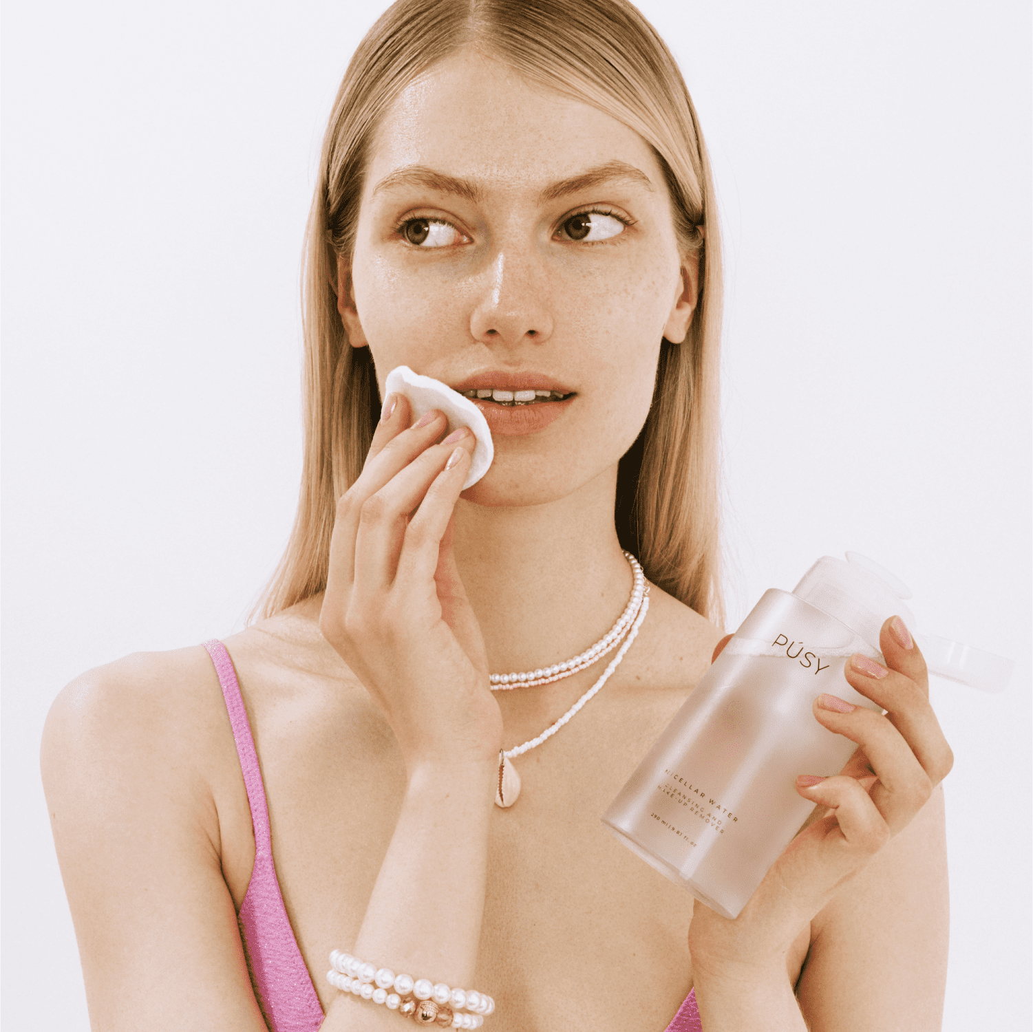 Woman applying PÚSY Micellar Water for effortless makeup removal - Clean beauty skincare routine